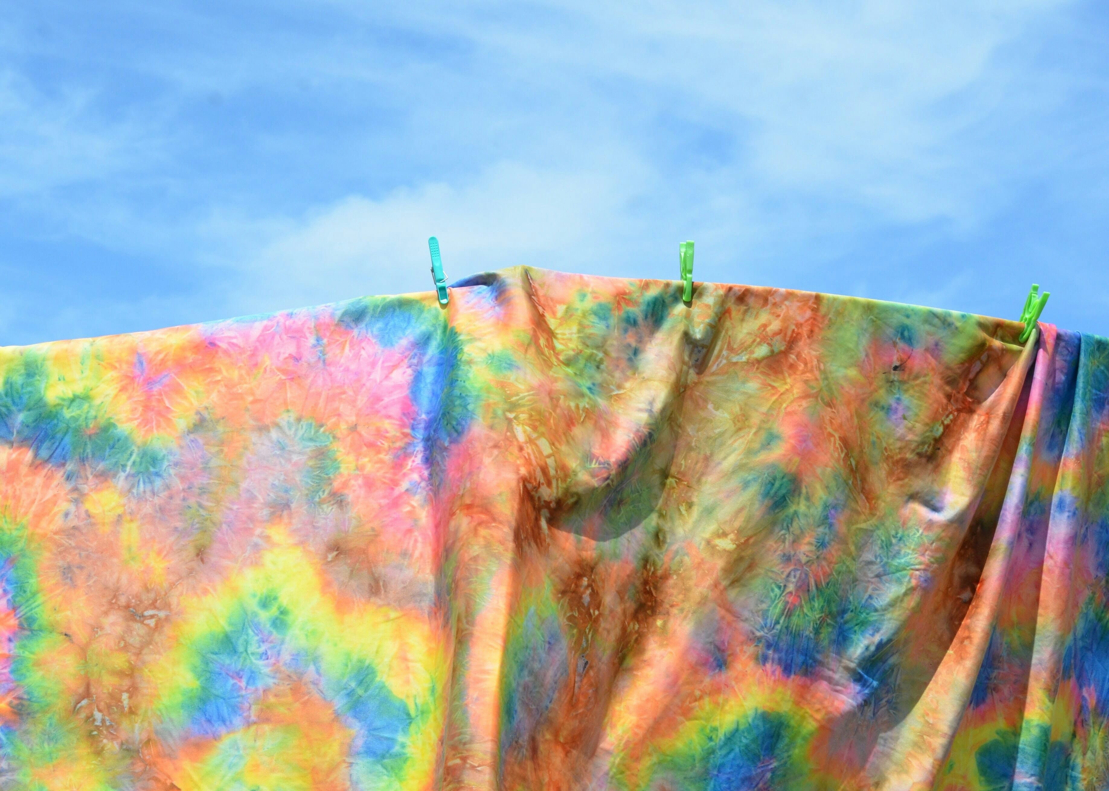 A tie dye sheet hanging from a clothes line